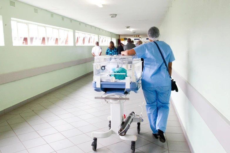 the elderly man in scrubs is hing a cart with medical supplies