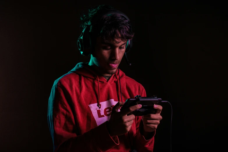 a man wearing a red hoodie holds a cellphone