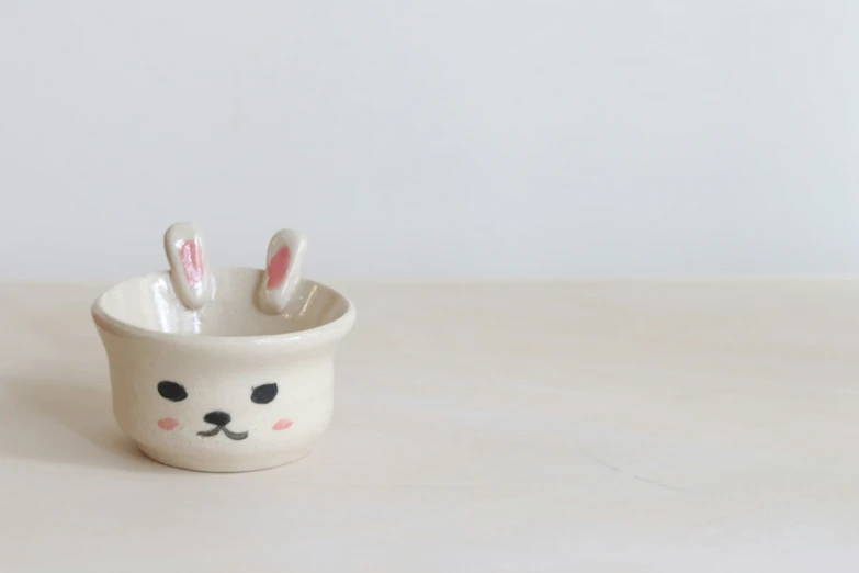 a cup with three ears that are shaped like rabbits
