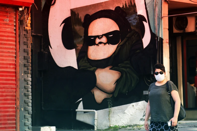 a woman wearing a mask in front of a wall mural