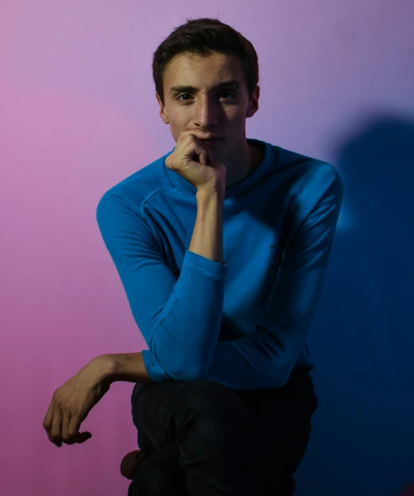 a young man leaning on a wall with his chin resting on his hands