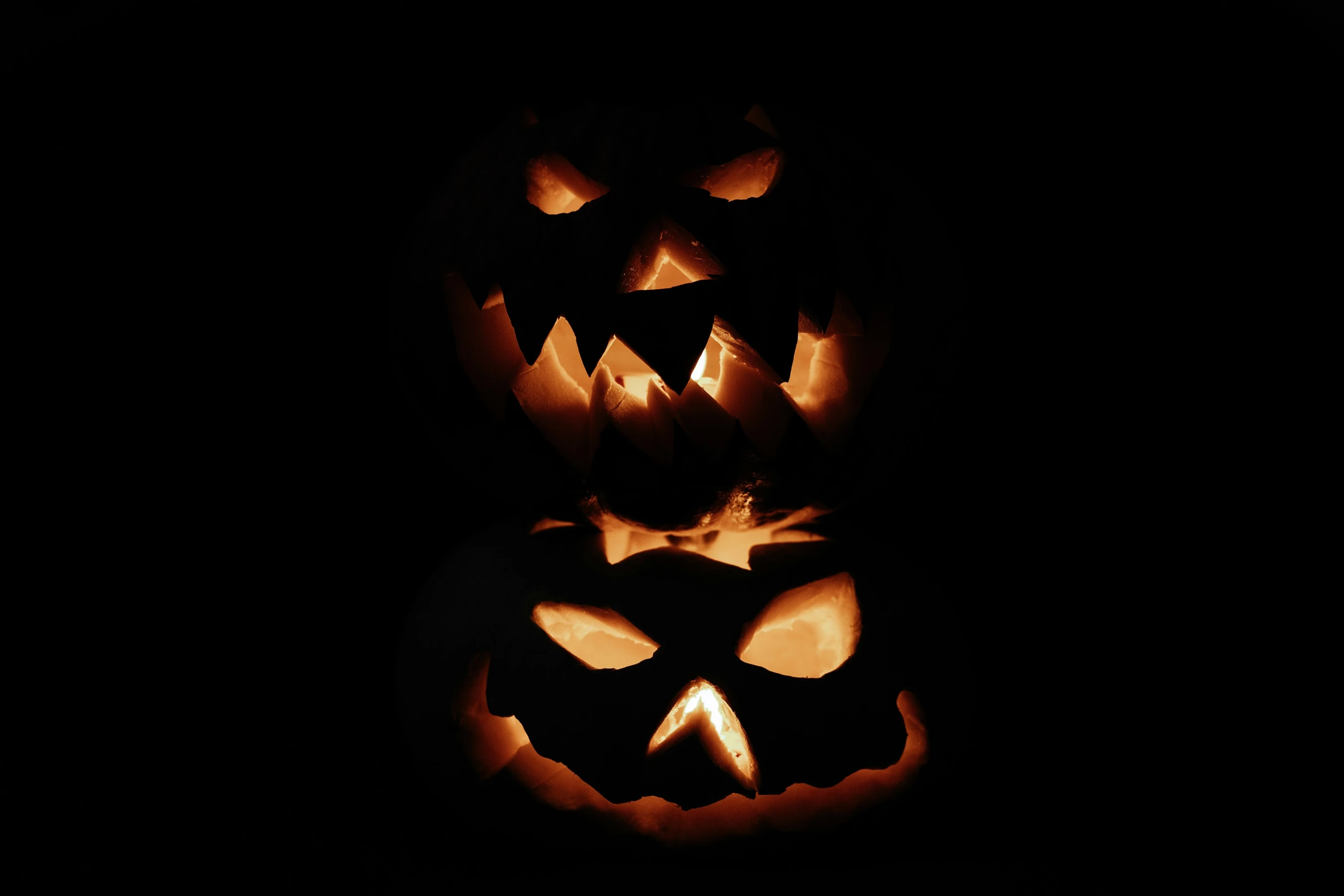 three carved pumpkins that have been glowing at night