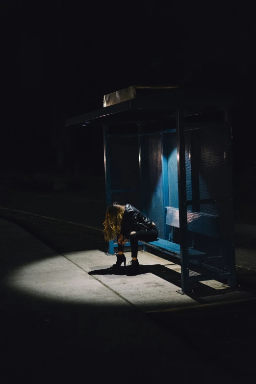 someone on a bench in the dark under an umbrella