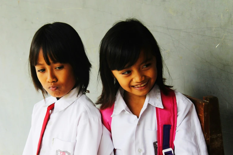 two girls wearing school uniforms stand next to each other