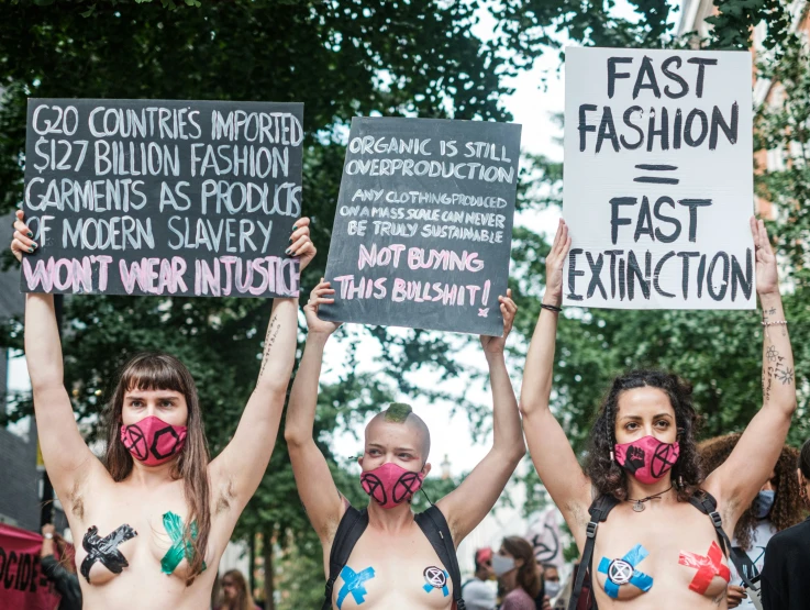 two women wearing face masks holding signs while protesting against sex