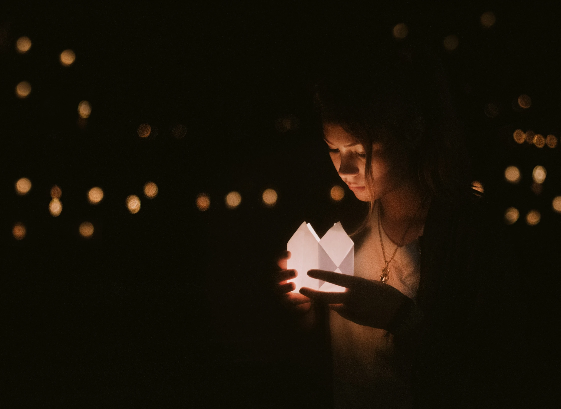 a woman holding a paper lantern in her hands