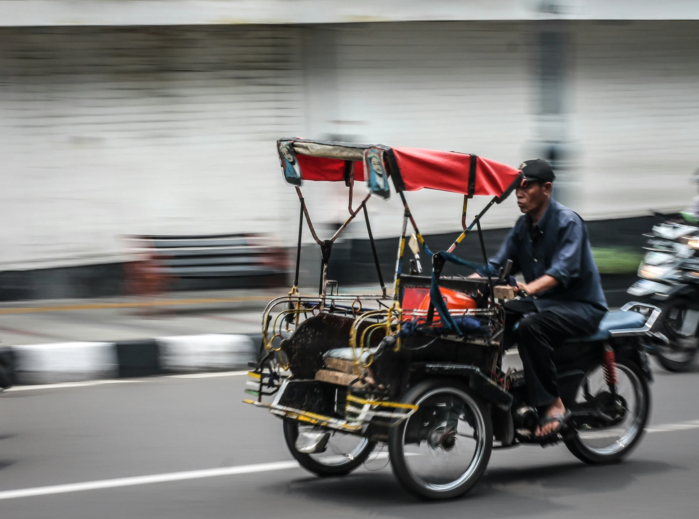 a man riding a small bike with a red canopy