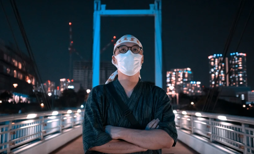 a man wearing a face mask on top of a bridge