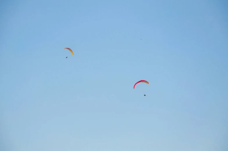 three parasails fly across the blue sky in a sunny day