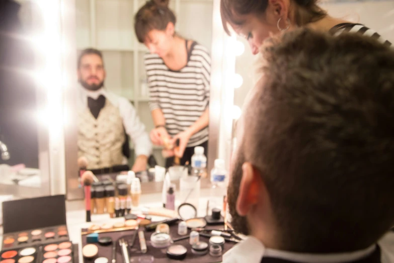 two people looking into a mirror at a make up and cosmetics table