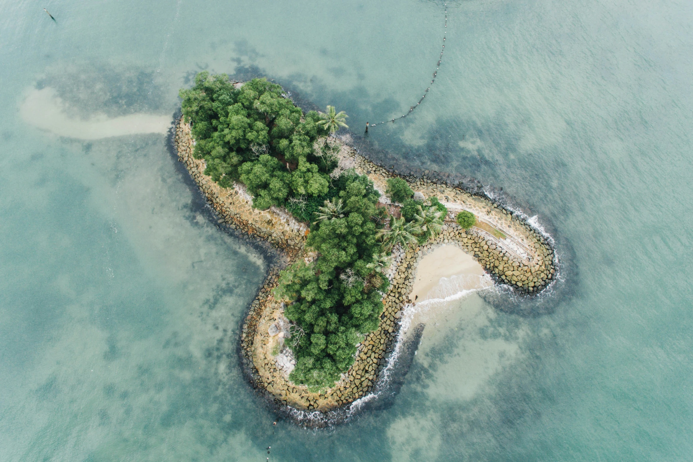 an island surrounded by small trees on the ocean