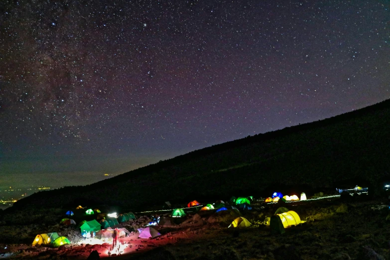a night view of the mountains and sky with several tents