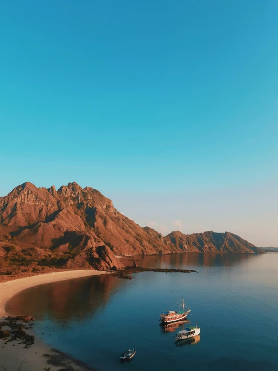 two boats floating in a body of water next to the mountains