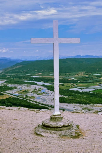a lone white cross sitting on top of a hill