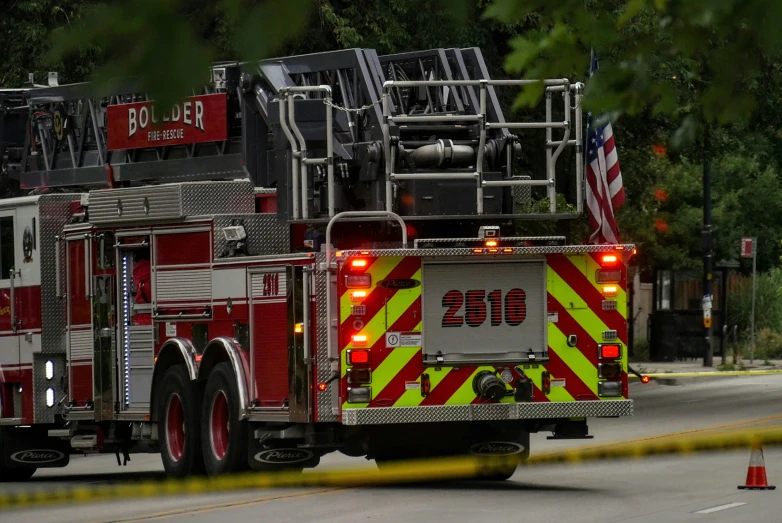 two fire trucks parked on a street in front of trees