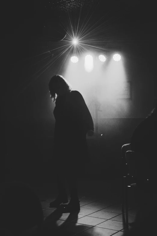 a man standing in the dark next to some empty chairs