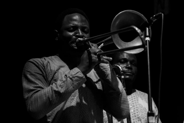 a man standing next to another man while playing a trombone