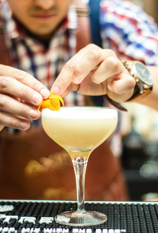 a bartender putting an orange peel on top of the glass