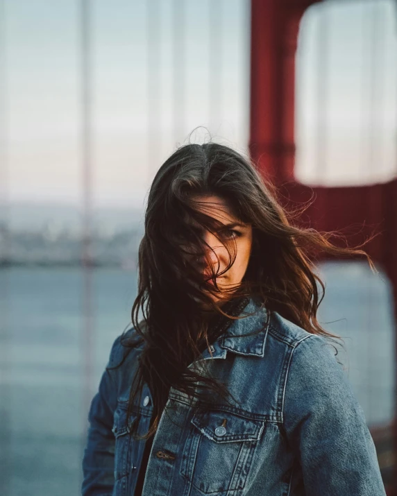 a woman in denim jacket leaning against a wall