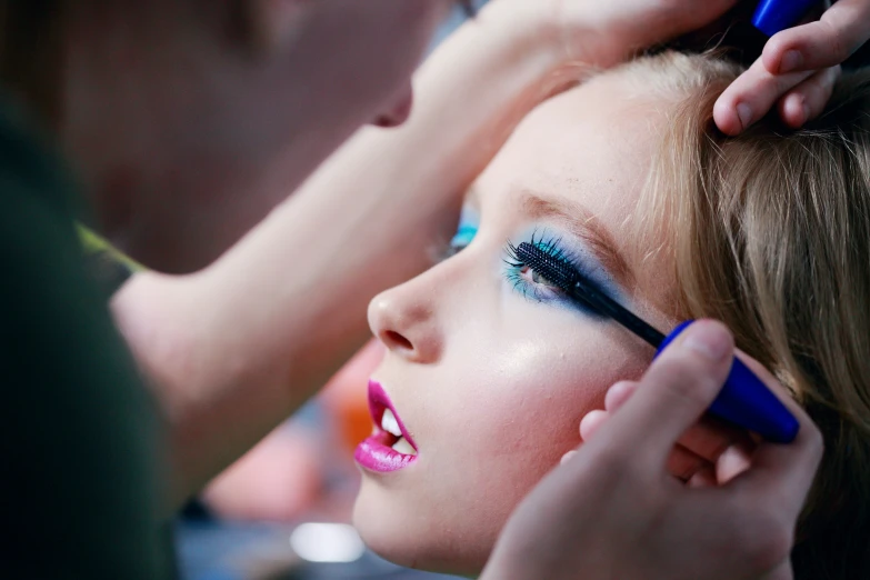 a woman putting her makeup on a man