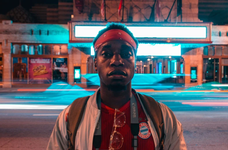 a young man standing in front of a building with lights on