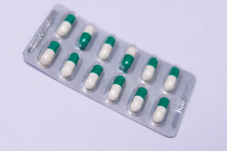 three rows of pill packs with white and green pills