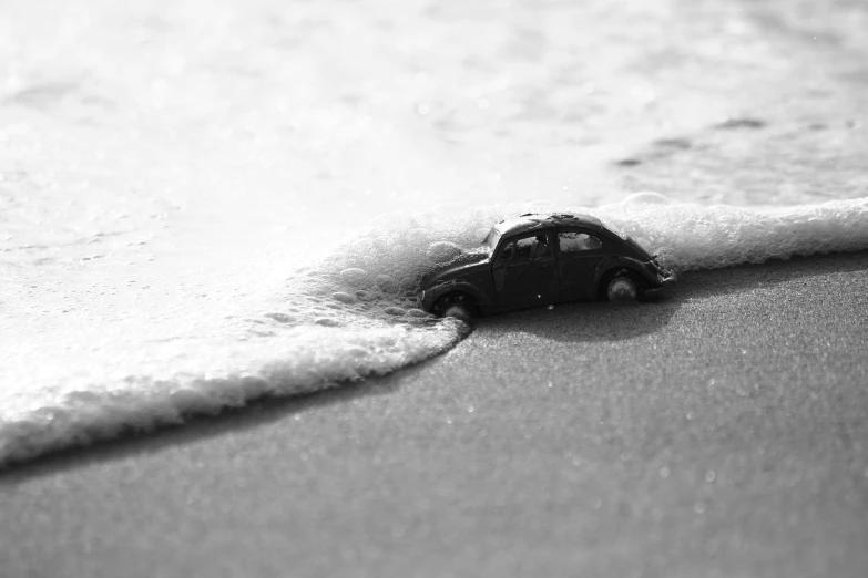 a toy car stuck in the sand of the beach