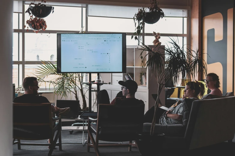 people in chairs watching television in an office setting