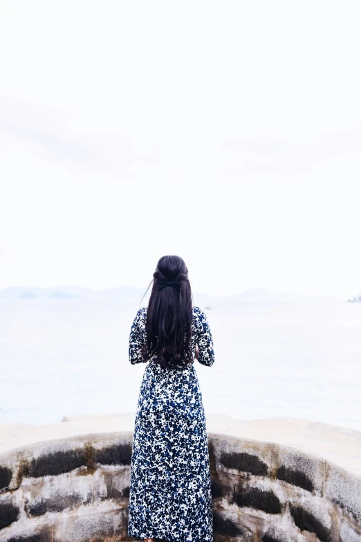 woman looking out at a sea from top of a wall