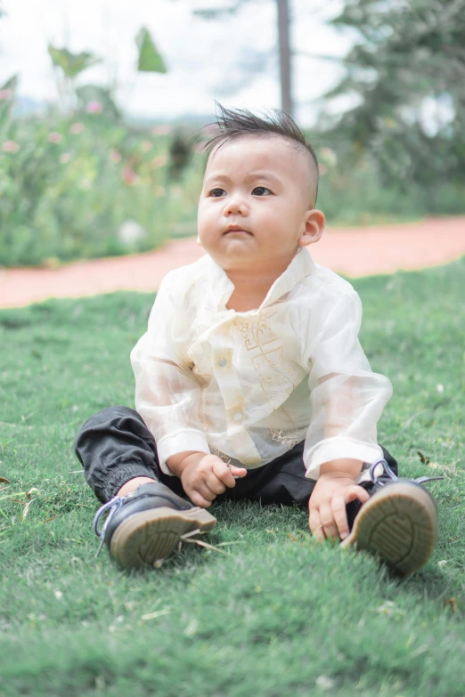 small  sitting in the grass wearing a white shirt and black pants