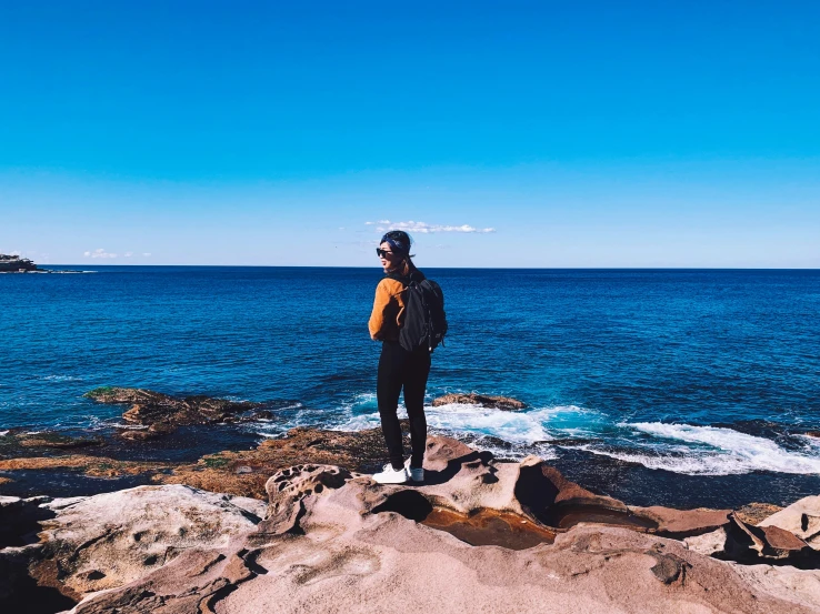 a person is standing on some rocks by the water