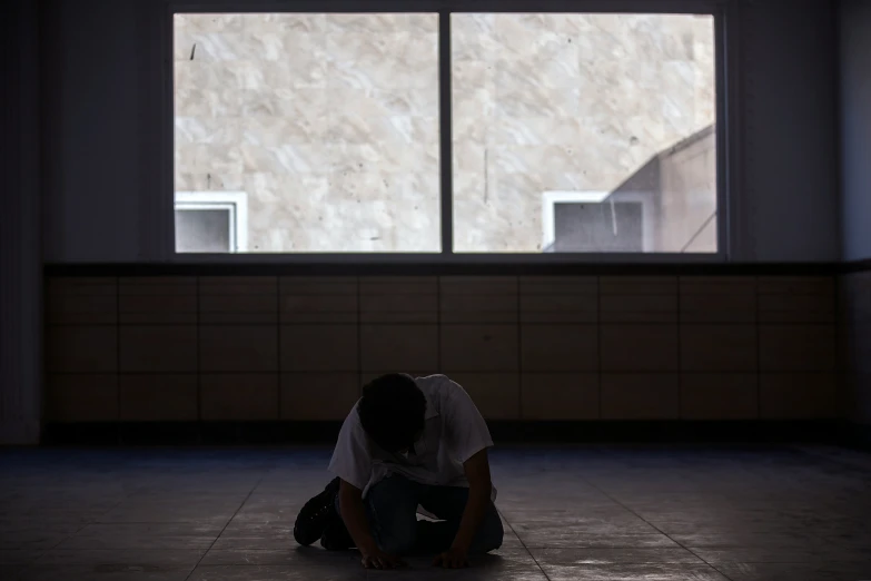 a man with his head down and wearing a hat in an empty room