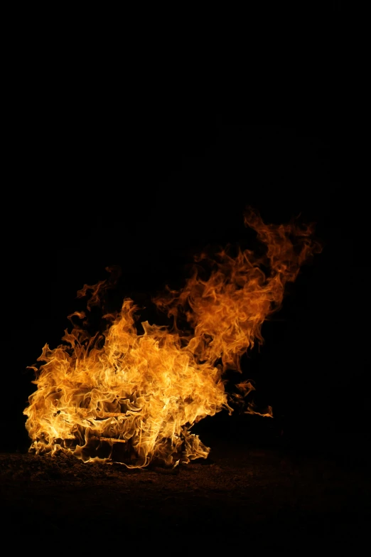 a large fire burning on top of a sandy beach