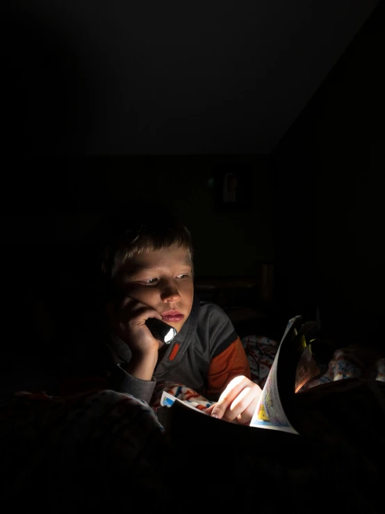 a young child holding a cellphone in the dark