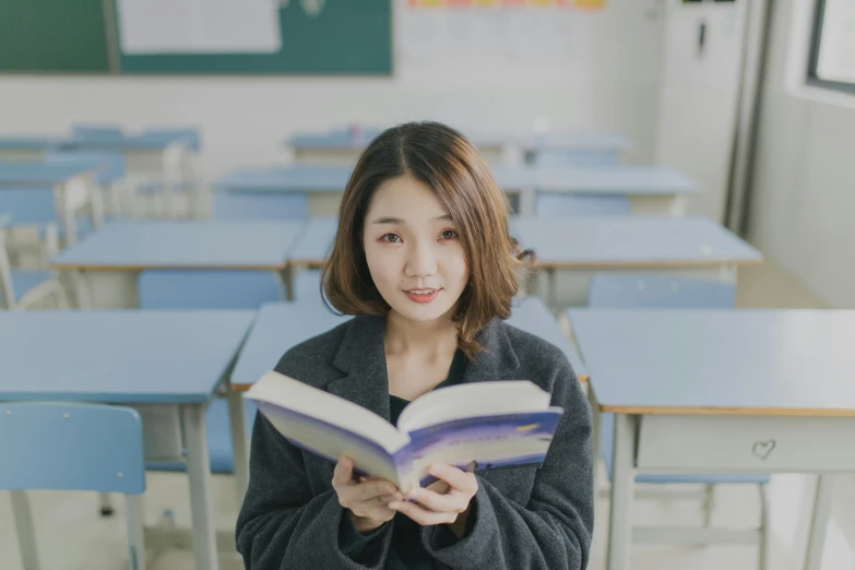 a young woman is holding a book in her hands