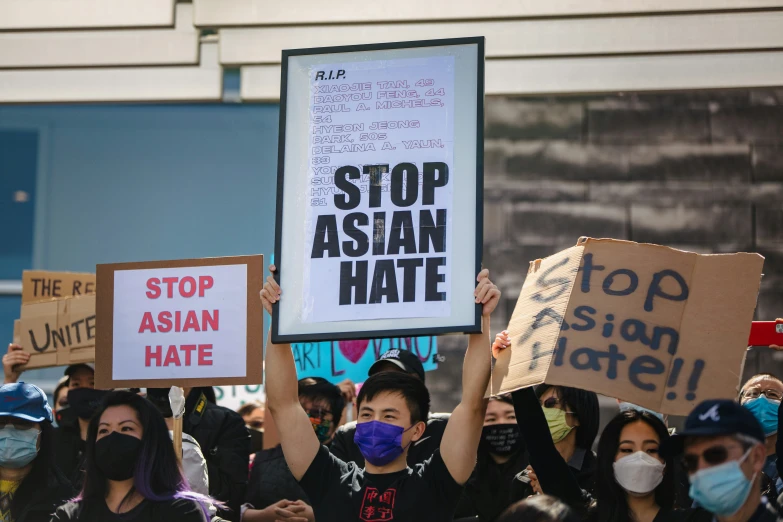 protesters hold placards with asian hate signs