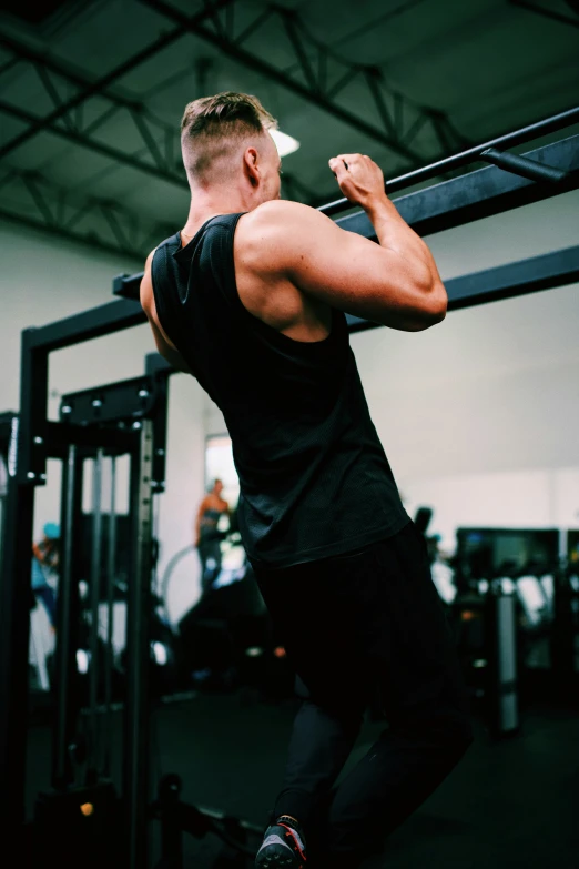 man in black tank top doing chin press in gym