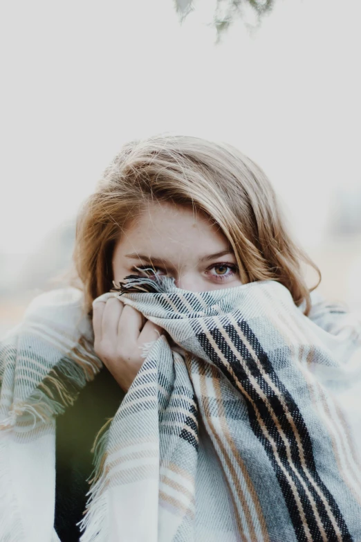 a woman covering her face with a blanket