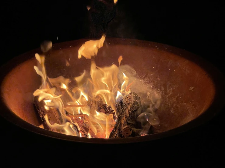 fire burns in a metal bowl with yellow flames