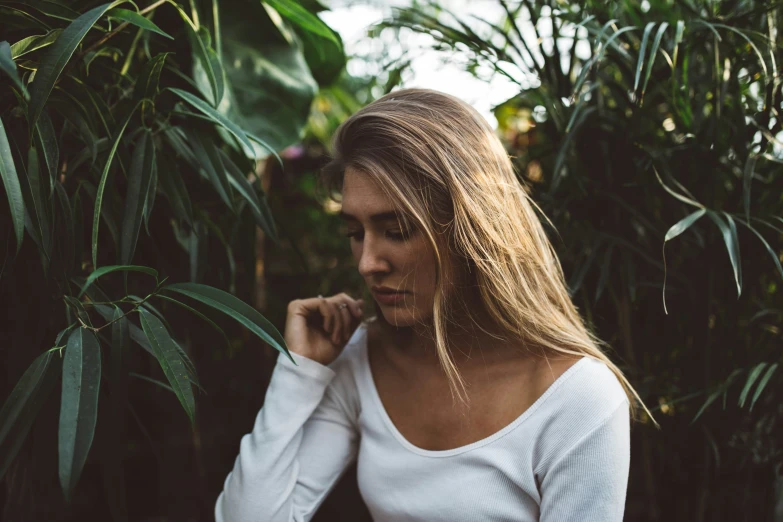 a woman poses in front of a grove of plants