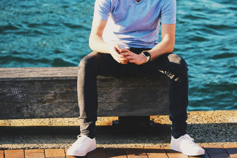 a man sitting on a wooden post over looking the water