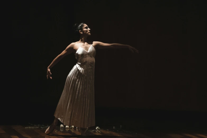 a woman is wearing a long white dress and stretching her arms out