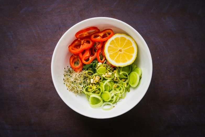 some assorted veggies in a bowl and an orange