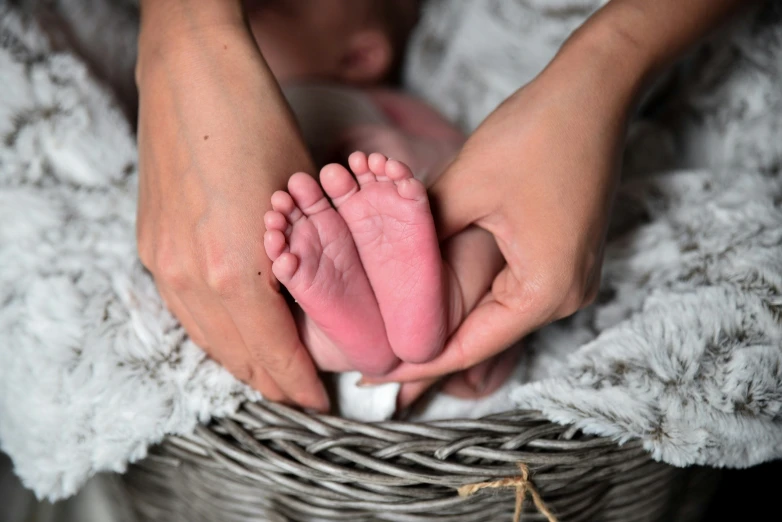 a person holds a newborn baby foot in their hands