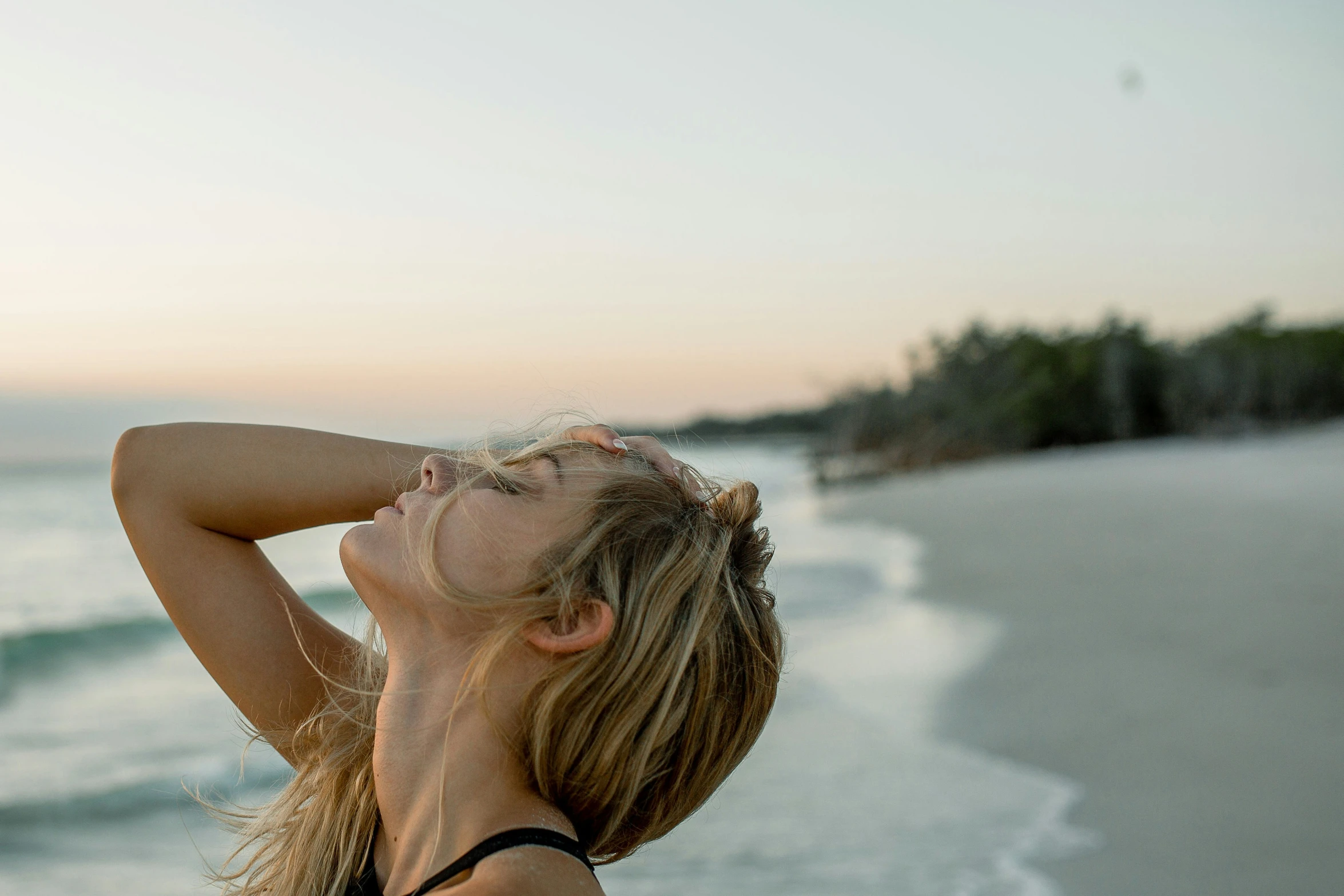 the girl is posing on the beach with her head in her hands