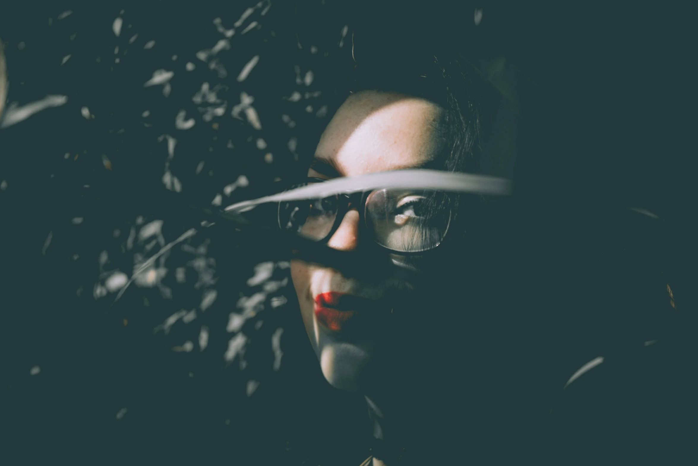 a woman in glasses holds up her scissors