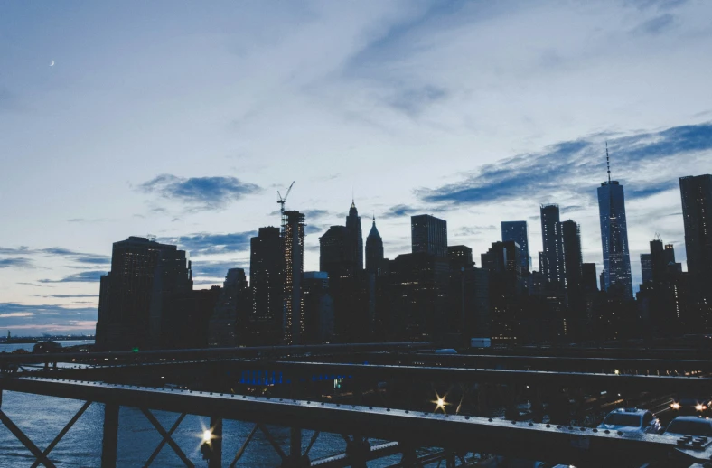 a city scene at dusk with a bridge crossing a river