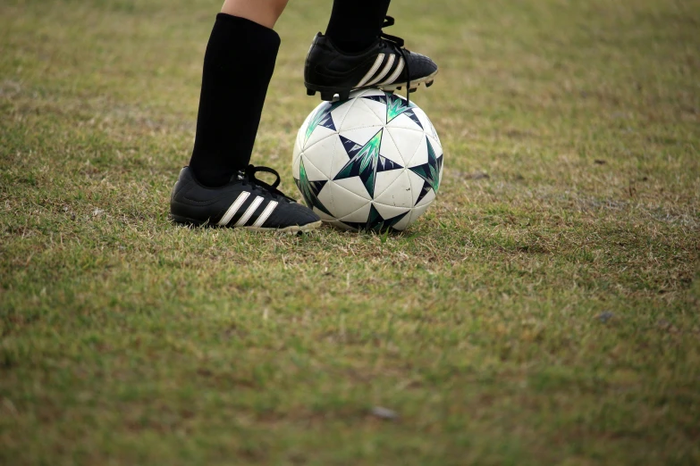 a person in black boots standing with a soccer ball