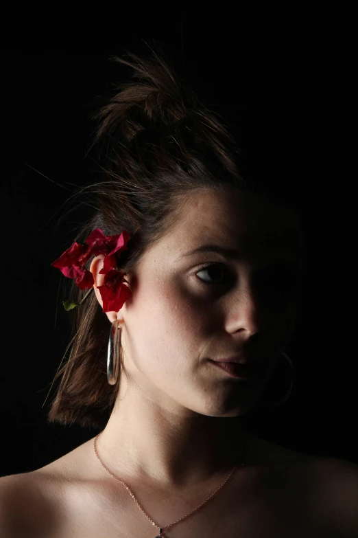 a young woman wearing red earrings and a flower in her hair