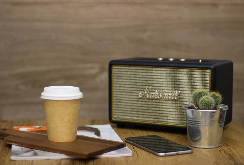 a cup with a coffee cup sitting next to a radio